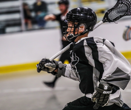 A child plays lacrosse in a rink
